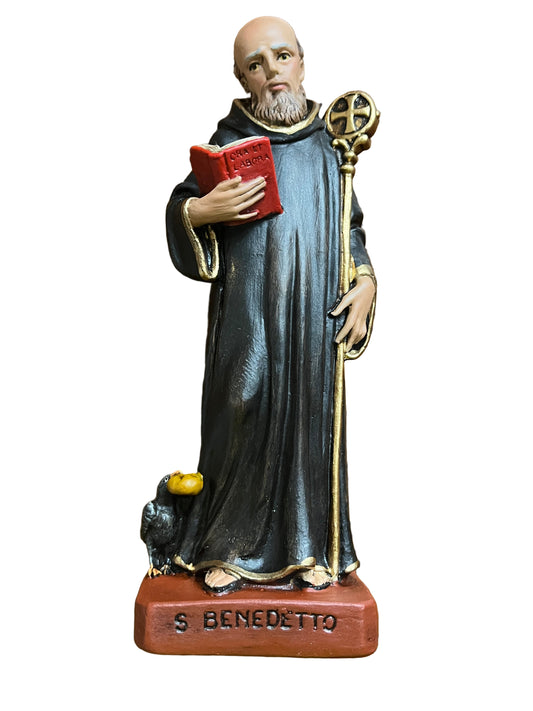 6 1/2" statue of St. Benedict holding a red book and staff, dressed in black robe with gold trim on base labeled S Benedetto