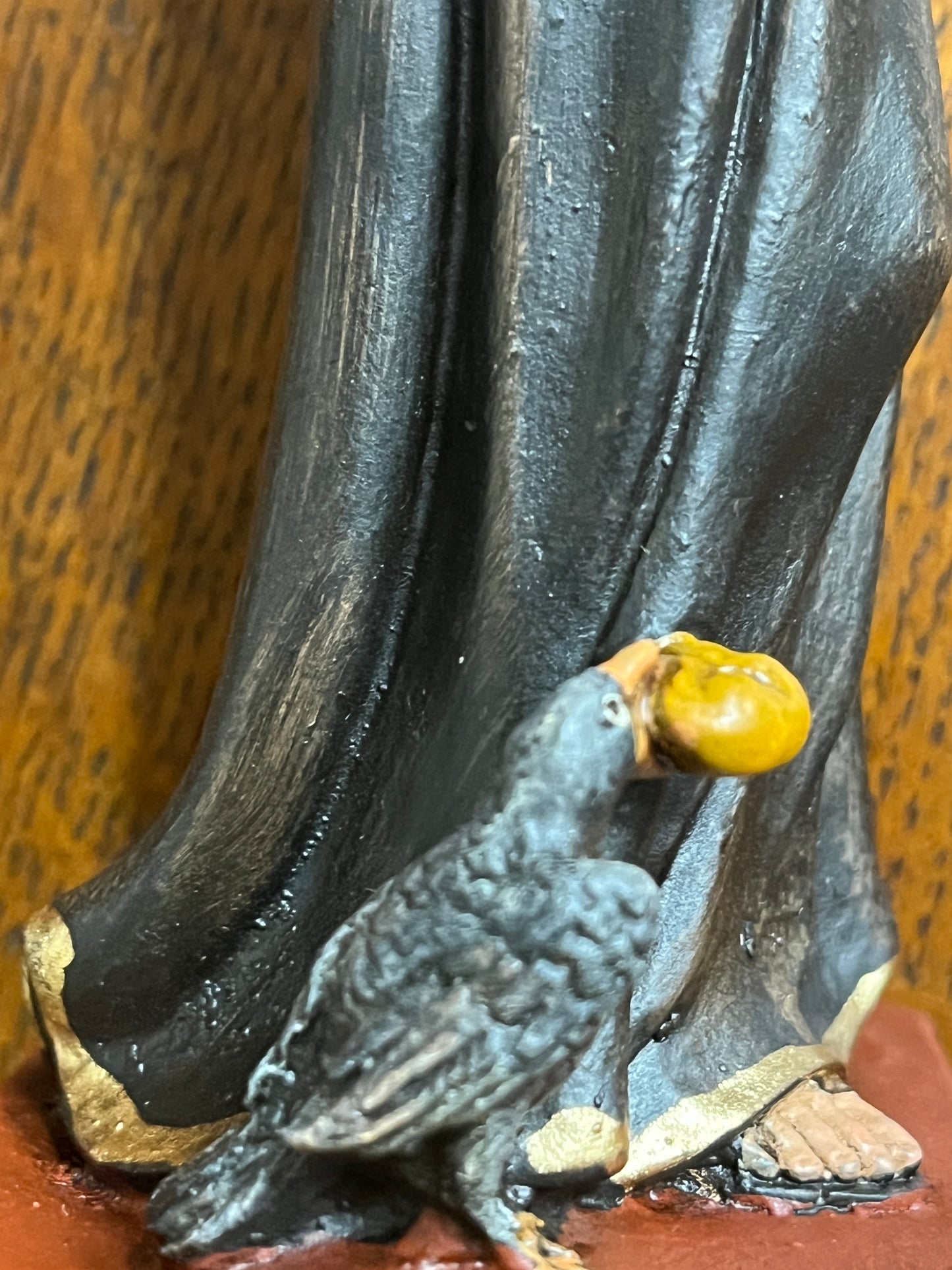 Close-up of 6 1/2" St. Benedict statue base showing detailed raven holding a golden object on red platform