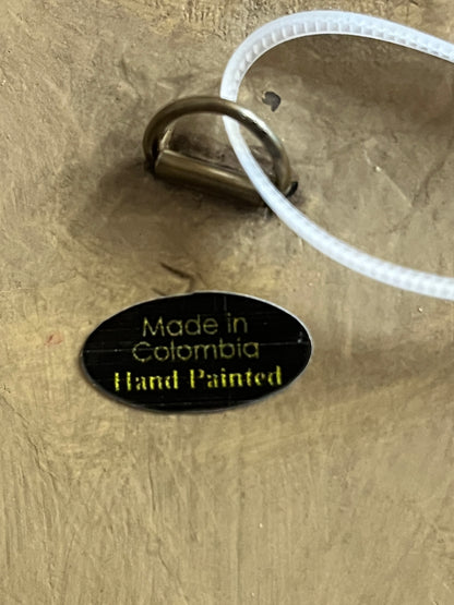 Oval black label with gold text reading Made in Colombia Hand Painted on wood plaque back