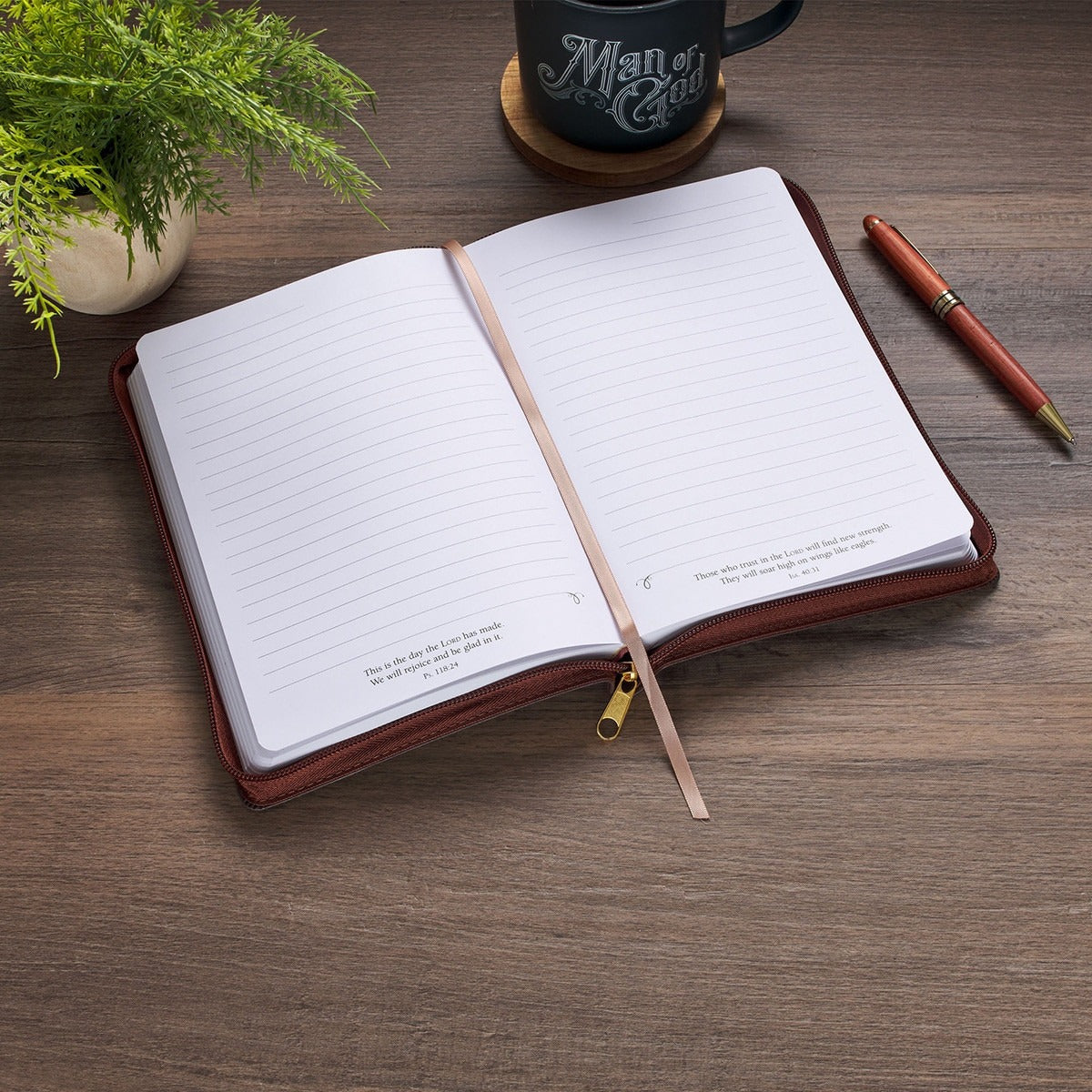 Open two-tone brown faux leather journal with zipper, lined pages, Isaiah 46:4 scripture, and satin ribbon marker on wood table