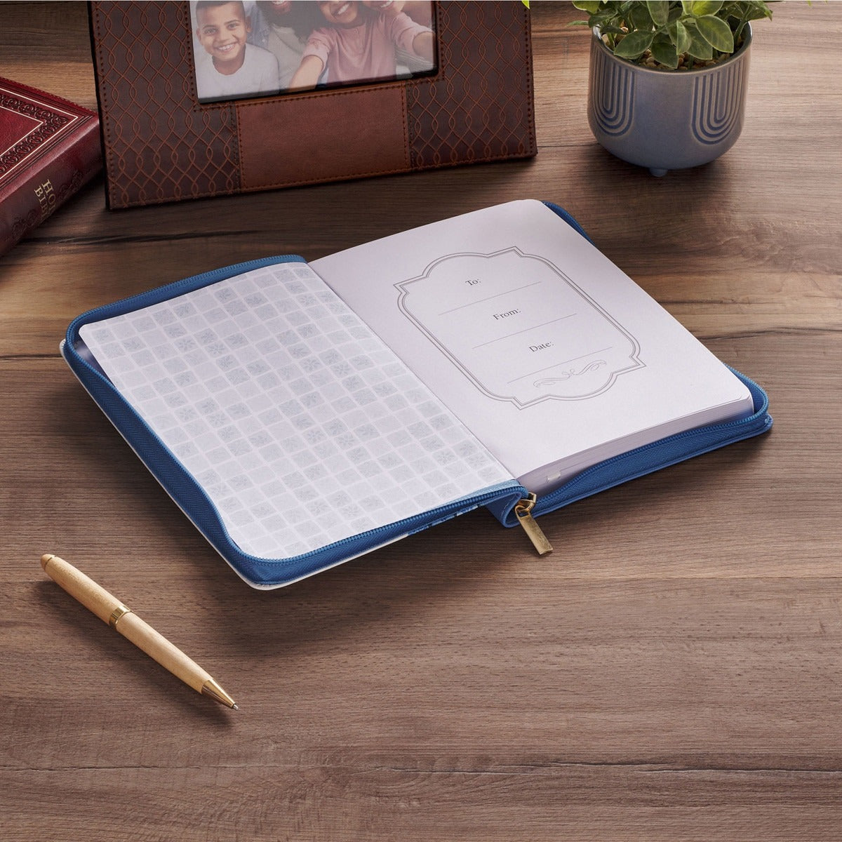Blue floral tile faux leather journal with zipper closure, open to lined pages with name and date section on wooden table