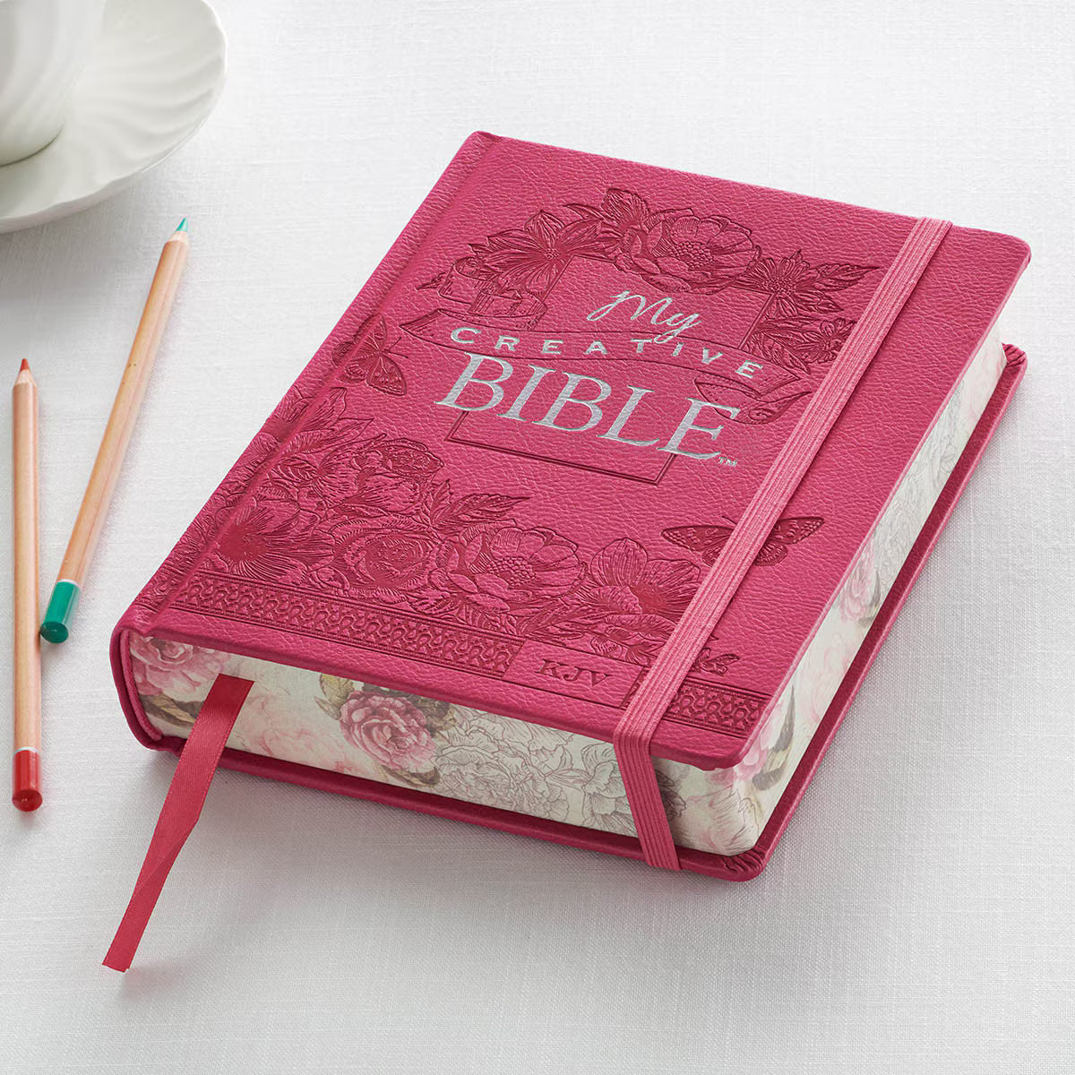Bright pink faux leather hardcover KJV My Creative Bible with floral embossed cover and matching elastic band closure
