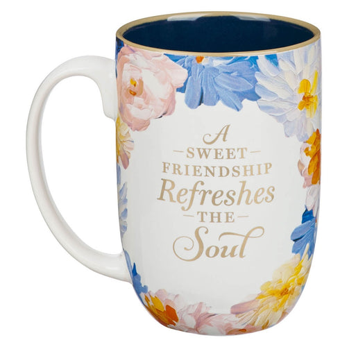 Ceramic mug with watercolor floral design and gold text reading "A sweet friendship refreshes the soul" inside blue rim