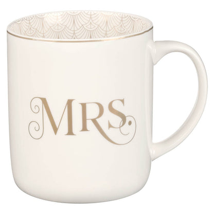 White ceramic coffee mug with gold "MRS." lettering and delicate gold pattern inside rim, part of newlywed set