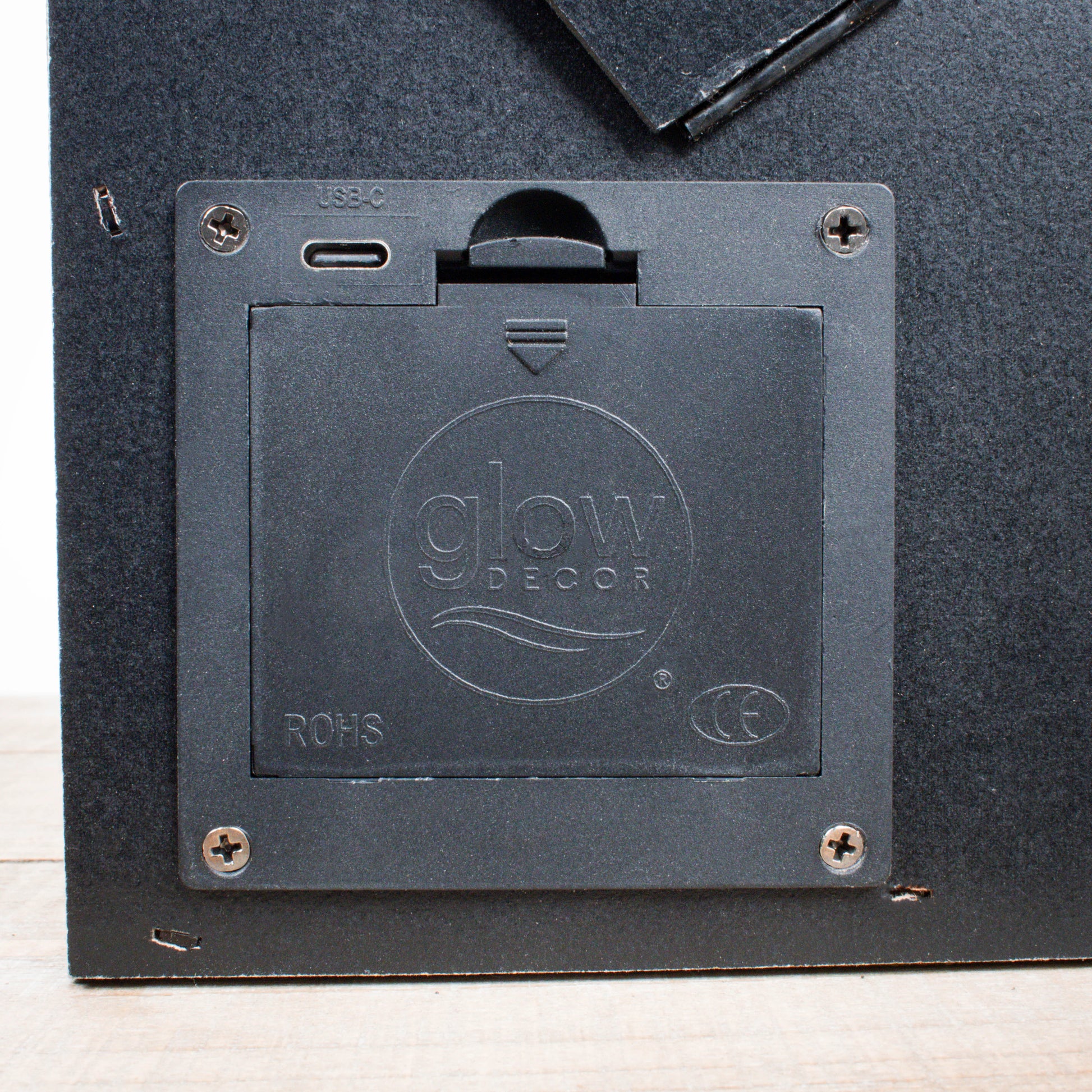 Black plastic battery compartment with USB-C port and Glow Decor logo on back of tabletop canvas frame