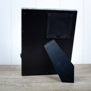 Back of Journey to Bethlehem lighted mini tabletop canvas picture showing battery compartment and stand on wooden surface