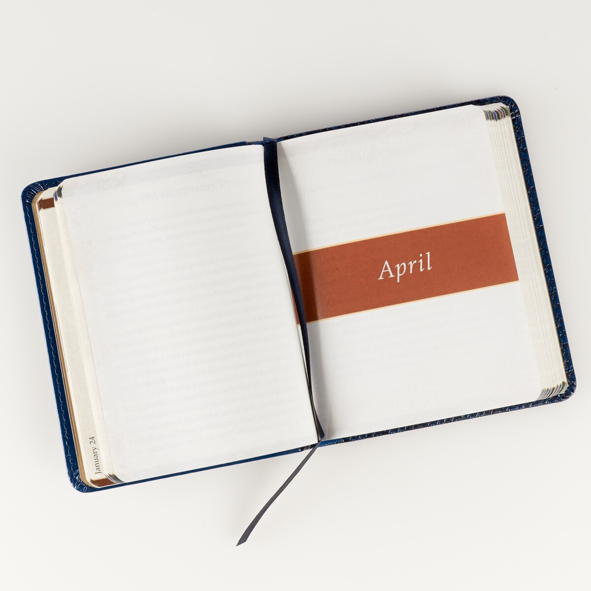 Open Faith's Checkbook one-minute devotions with navy blue faux leather cover showing April monthly section divider