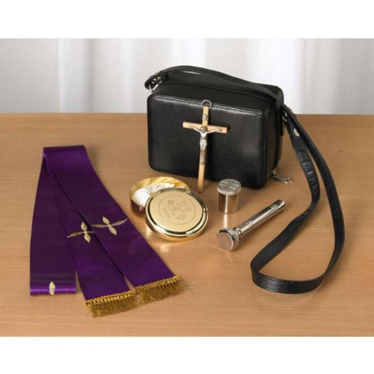 Traveling Pastoral Sick Call Set with black carrying case, purple stole, pyx, crucifix, and holy oil container on wooden table