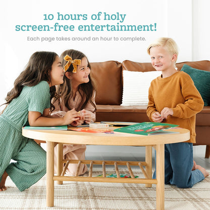 Three children smiling and playing with the Pray by Sticker Christmas sticker book at wooden table