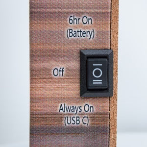 Close-up of light switch on wood grain surface for Journey to Bethlehem lighted mini tabletop canvas with timer options