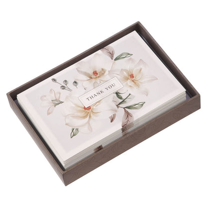 Set of white magnolia thank you note cards with delicate floral design and elegant script in decorative box