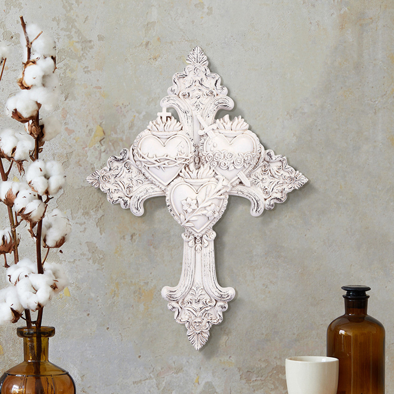White ornate wall cross featuring the three Sacred Hearts of Jesus, Mary, and Joseph on decorative background