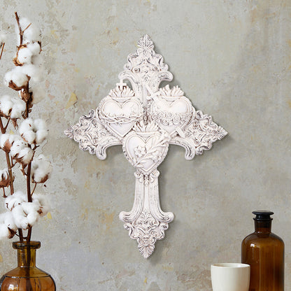 White ornate wall cross featuring the three Sacred Hearts of Jesus, Mary, and Joseph on decorative background