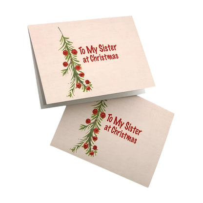 Christmas card for sister with simple evergreen and red berry design and "To My Sister at Christmas" text on cream background