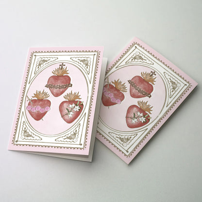 Valentine greeting card with Sacred Heart, Immaculate Heart, and Chaste Heart illustrations framed in gold on pink background