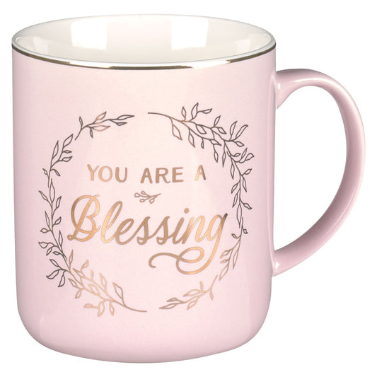 Pink ceramic coffee mug with gold “You Are A Blessing” text and decorative leaf wreath design