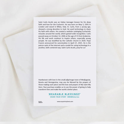 Back of Saint Carlo Acutis bracelet card with biography text and Wearable Blessings logo on white background