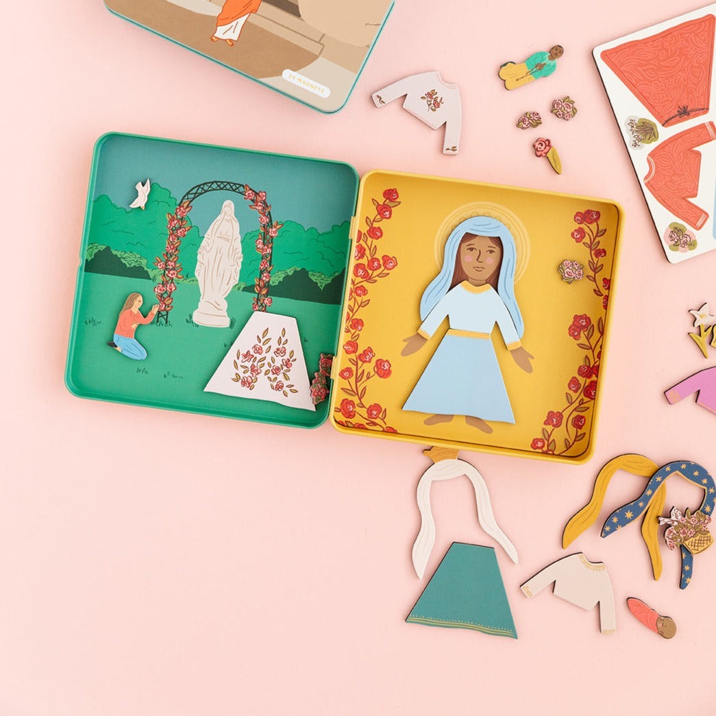 Open Mary Dress Up Magnet Playset with illustrated Catholic church scene and dress-up magnet pieces on pink background